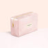 The Pink Lurex Pouch by Manucurist-us is a rectangular cosmetic bag in light pink with a shimmering finish, highlighted by a gold zipper and the Manucurist Paris label on the front. Set against a soft peach and white background, this pouch is perfect for storing your manicure essentials, effortlessly blending style and practicality for everyday glamour.