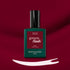 A bottle of Amour LED nail polish by Manucurist rests on a deep red surface with a brush stroke of white polish below it, highlighting the luminous burgundy hue of this signature gel polish.
