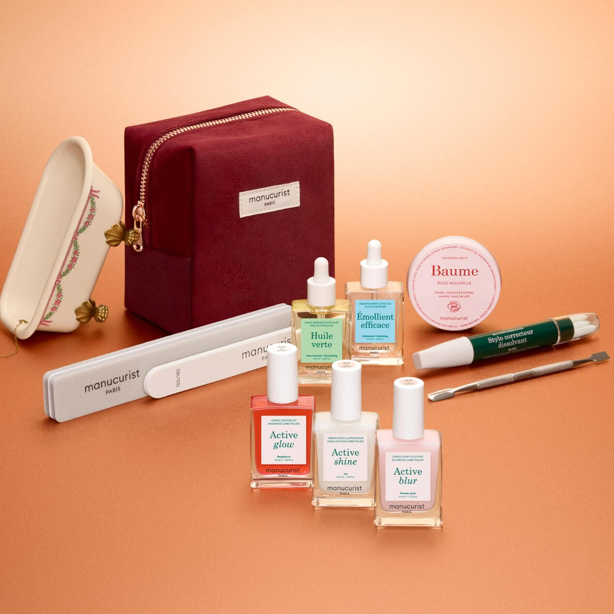 Présenté sur un fond pêche, le coffret cadeau ultime Active™ de Manucurist comprend des vernis à ongles, des huiles nourrissantes, un baume, un bloc polissoir, une lime, un accessoire de manucure, une petite coupelle en porcelaine et une pochette bordeaux zippée ornée du logo Manucurist. De quoi enrichir votre routine manucure ou offrir un cadeau attentionné à une personne qui aime prendre soin de ses ongles.