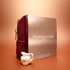 Un Active™ Gift Set Holiday de Manucurist, composé d’une pochette bordeaux et d’une boîte métallisée portant l’inscription « Manucurist Paris », est présenté sur une surface orange, accompagné à l’avant d’un petit pot à lait en porcelaine blanche décoré de fleurs.