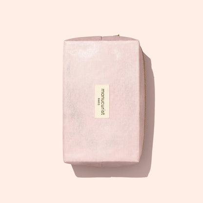 The Manucurist-us Pink Lurex Pouch is a rectangular, light pink cosmetic bag with a shimmering finish and a gold zipper. It features a front label reading “manucurist PARIS” and is photographed on a pale background—ideal for storing your manicure essentials.