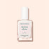 A clear glass bottle of Manucurist Active™ Shine Icy illuminating nail polish with a white cap, photographed against a pale peach background.
