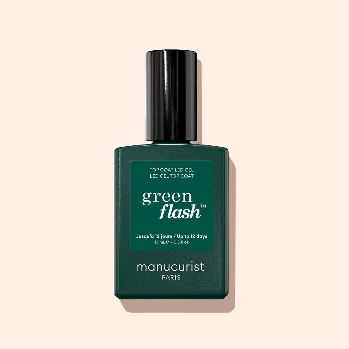 A dark green bottle of Manucurist Green Flash™ Top Coat stands upright on a light beige background, featuring white text and a black cap. This gel polish top coat promises up to 12-day shine for flawless nails.
