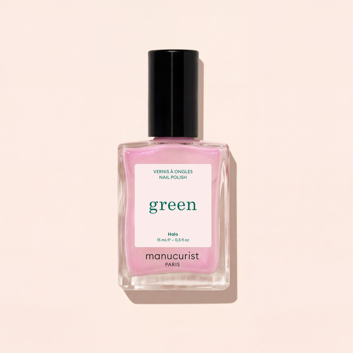 Un flacon carré en verre de vernis à ongles Manucurist dans la teinte Halo, un mauve laiteux avec un bouchon noir, est présenté sur un fond beige clair.