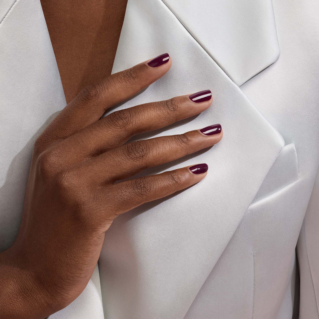 Gros plan sur une main portant le vernis gel Prune de Manucurist, un rouge vin profond, posée sur le revers d&