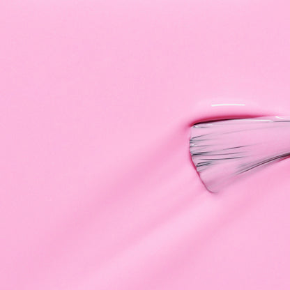 A close-up of a Manucurist paintbrush spreading their glossy neon pink "Candy" nail polish, revealing visible bristles and vivid texture on the right.