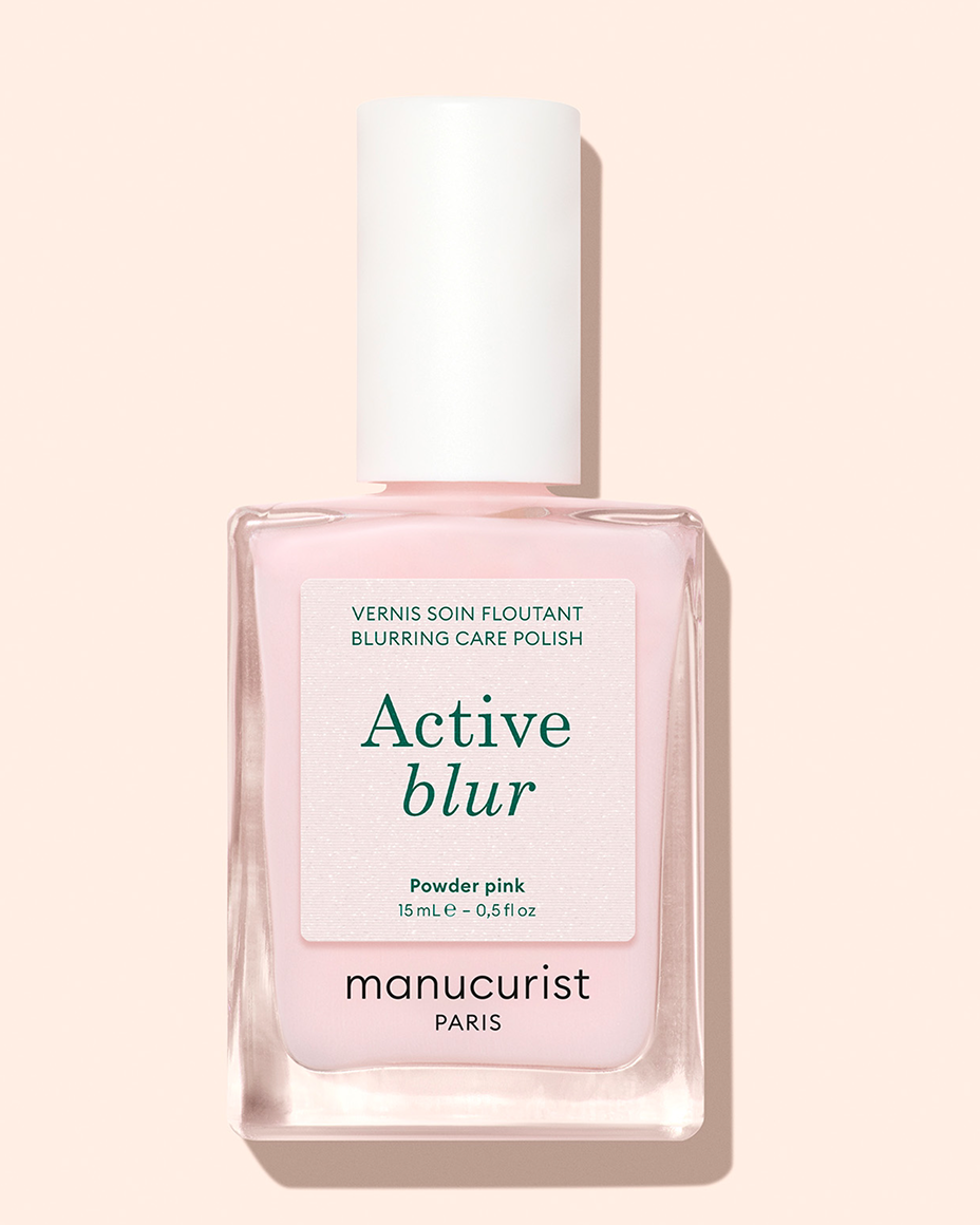 A bottle of Manucurist Paris Active Blur Blurring Care Polish in powder pink, featuring a white cap and minimalist label on a light pink background.