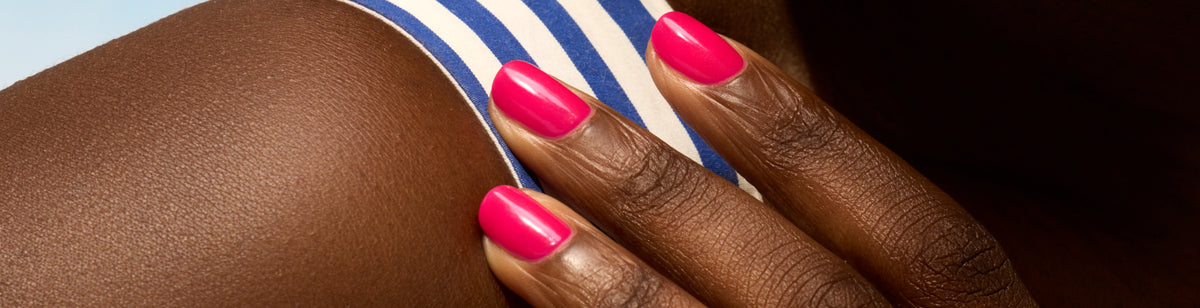 A close-up of a hand with bright pink nail polish resting on a persons shoulder, who is wearing a blue-and-white striped garment.