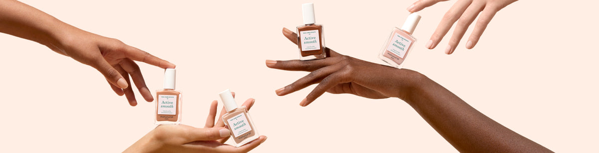 Several hands of different skin tones hold and display various shades of nail polish bottles against a pale, neutral background. The bottles are labeled Active Smooth with white caps.