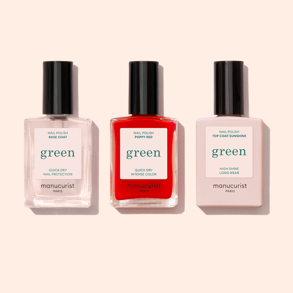 Three bottles of nail polish from Manucurist Paris on a pale background: a clear base coat, a bright red color labeled Poppy Red, and a pale pink top coat labeled Sunshine.