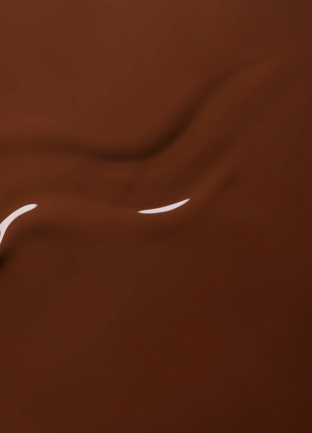 Du chocolat liquide brun, onctueux et riche, aux reflets brillants et aux délicats motifs tourbillonnants créant une texture soyeuse et appétissante.
