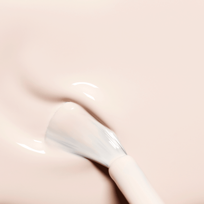A close-up of the Manucurist Crème brush spreading a creamy pale pink and off-white polish, revealing its glossy, wet texture on a smooth surface.