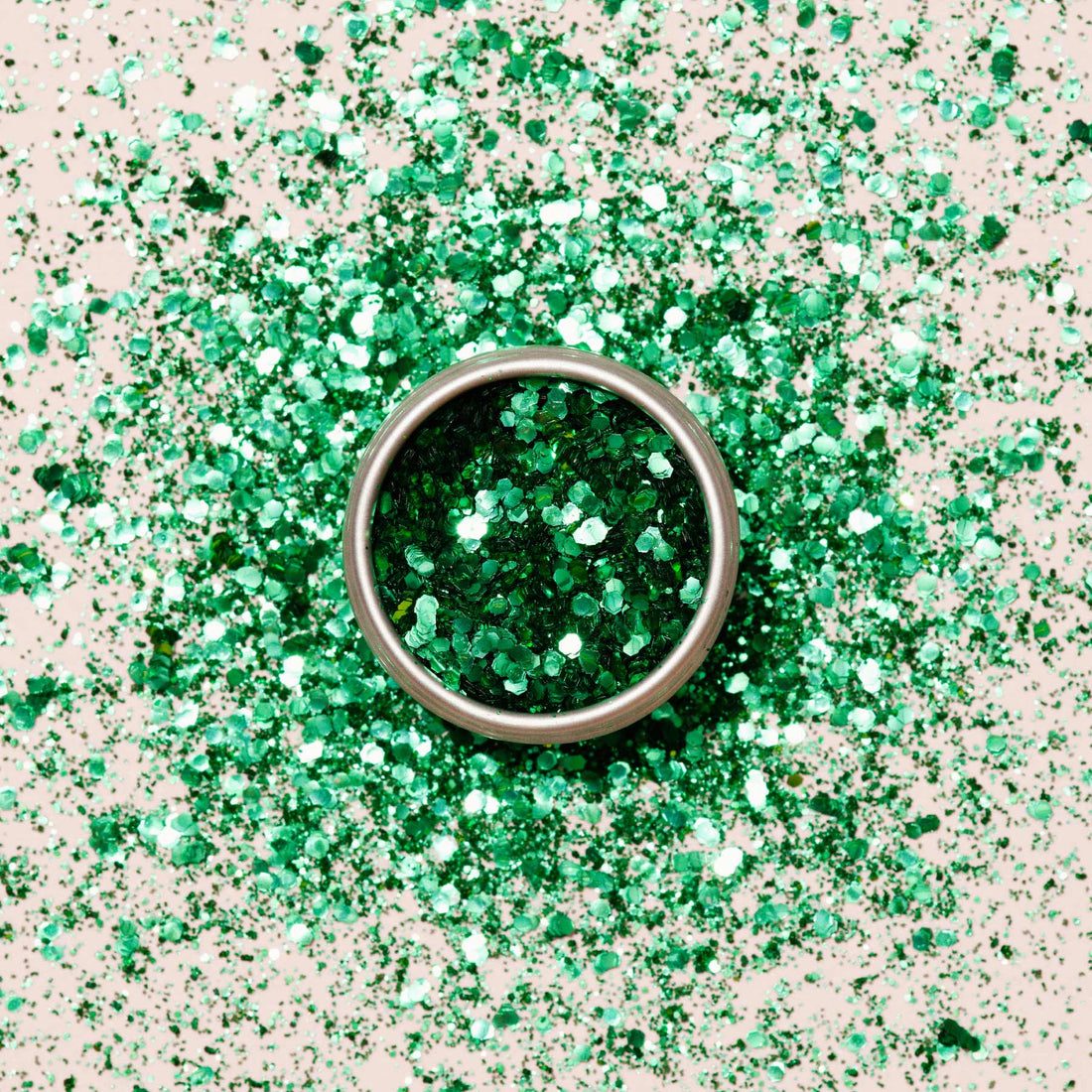 A round metal container of Manucurist Cactus Biodegradable Glitter sits on a surface, surrounded by scattered green glitter—perfect for creative nail art designs.