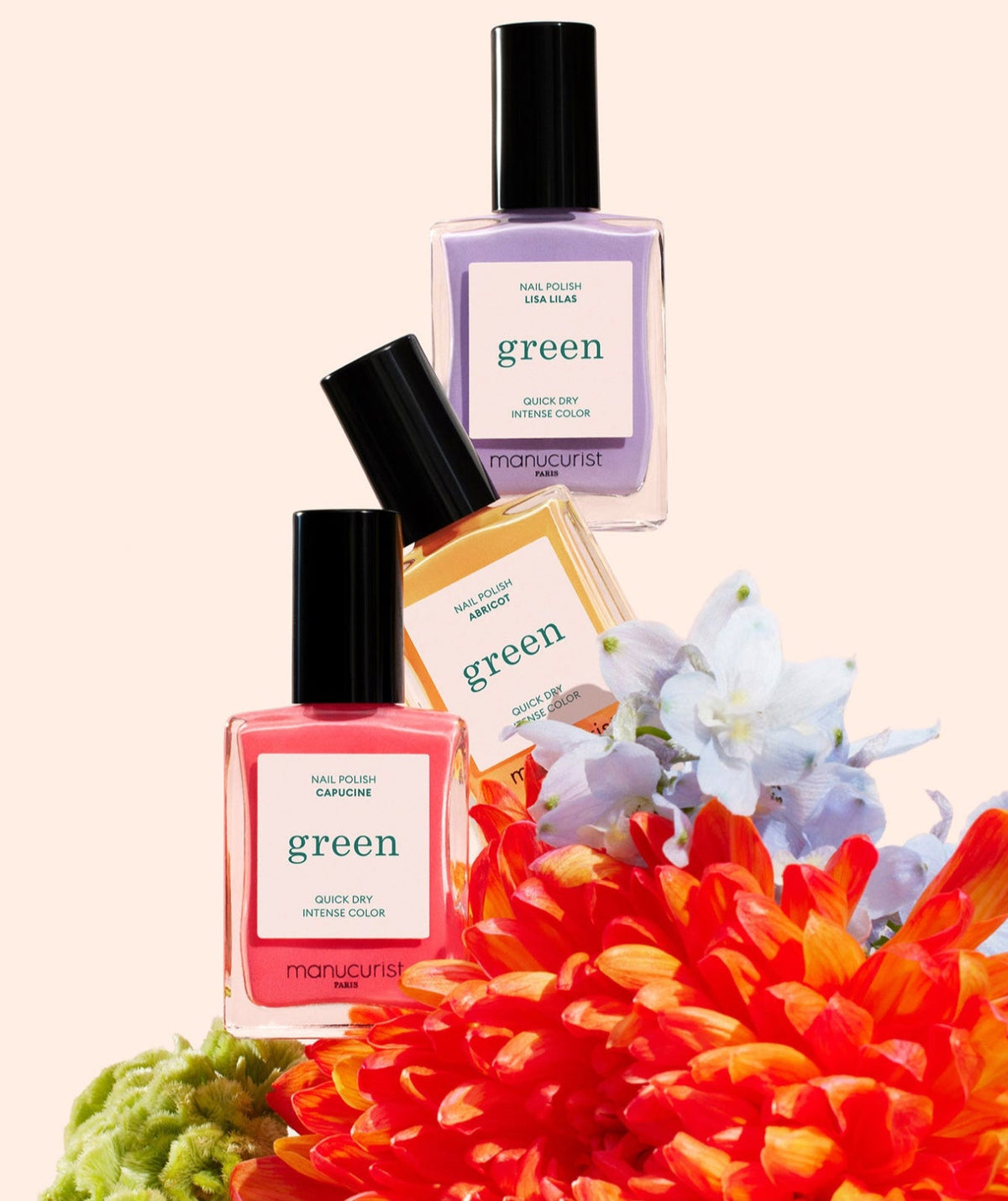 Three bottles of Manucurist nail polish in pink, red, and purple shades are displayed above bright orange and white flowers, with a light beige background.