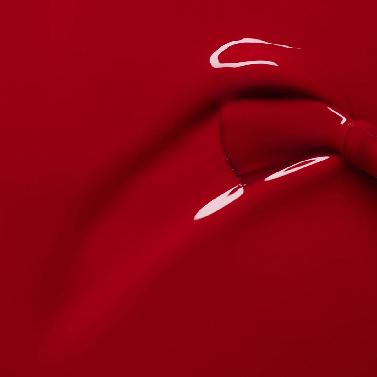 Gros plan sur le vernis semi-permanent rouge profond et brillant "Dark Dahlia" de Manucurist, mettant en valeur ses courbes lisses et ses reflets subtils, rappelant du latex tendu sur une forme.