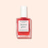 A bottle of Manucurist Active™ Glow Raspberry nail care polish, featuring a white cap and a pink label on a light peach background, provides plant-based nourishment for healthy, radiant nails.
