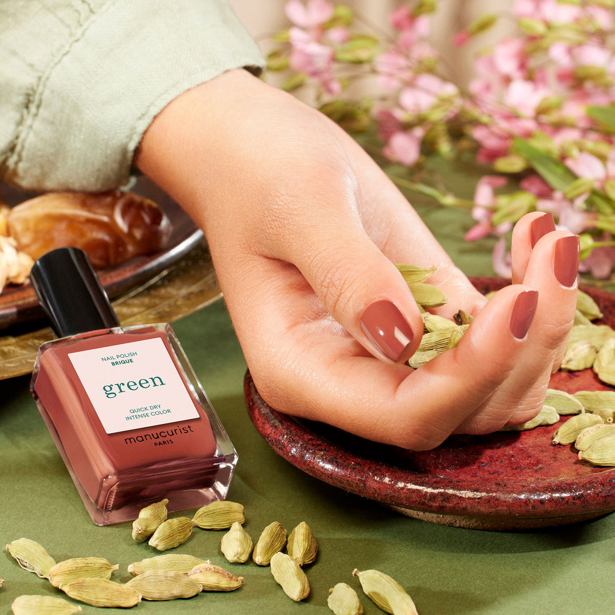 A hand with glossy, brownish-pink nails painted in Manucurist&