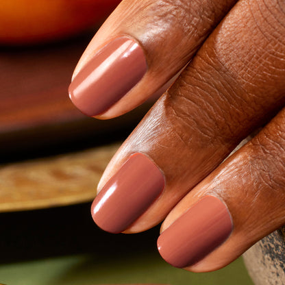 A close-up of a hand with medium to dark skin, featuring three neatly manicured nails painted in Manucurist’s Brique, a glossy shade beside muted mauve.