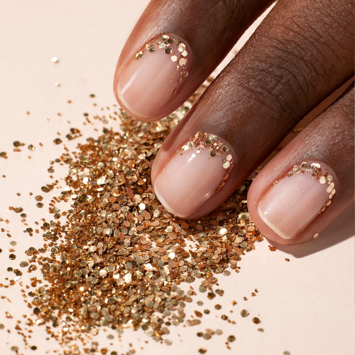 A hand with nude nails sparkles at the cuticles with Manucurist&