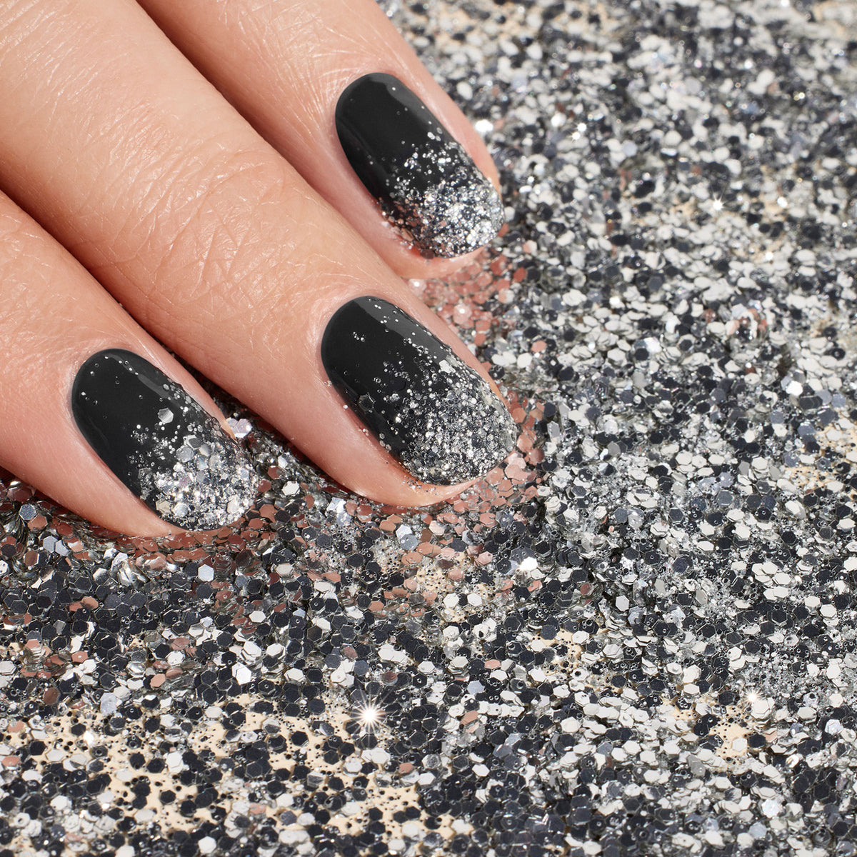 A hand with black and silver ombré nails, enhanced by Manucurist&