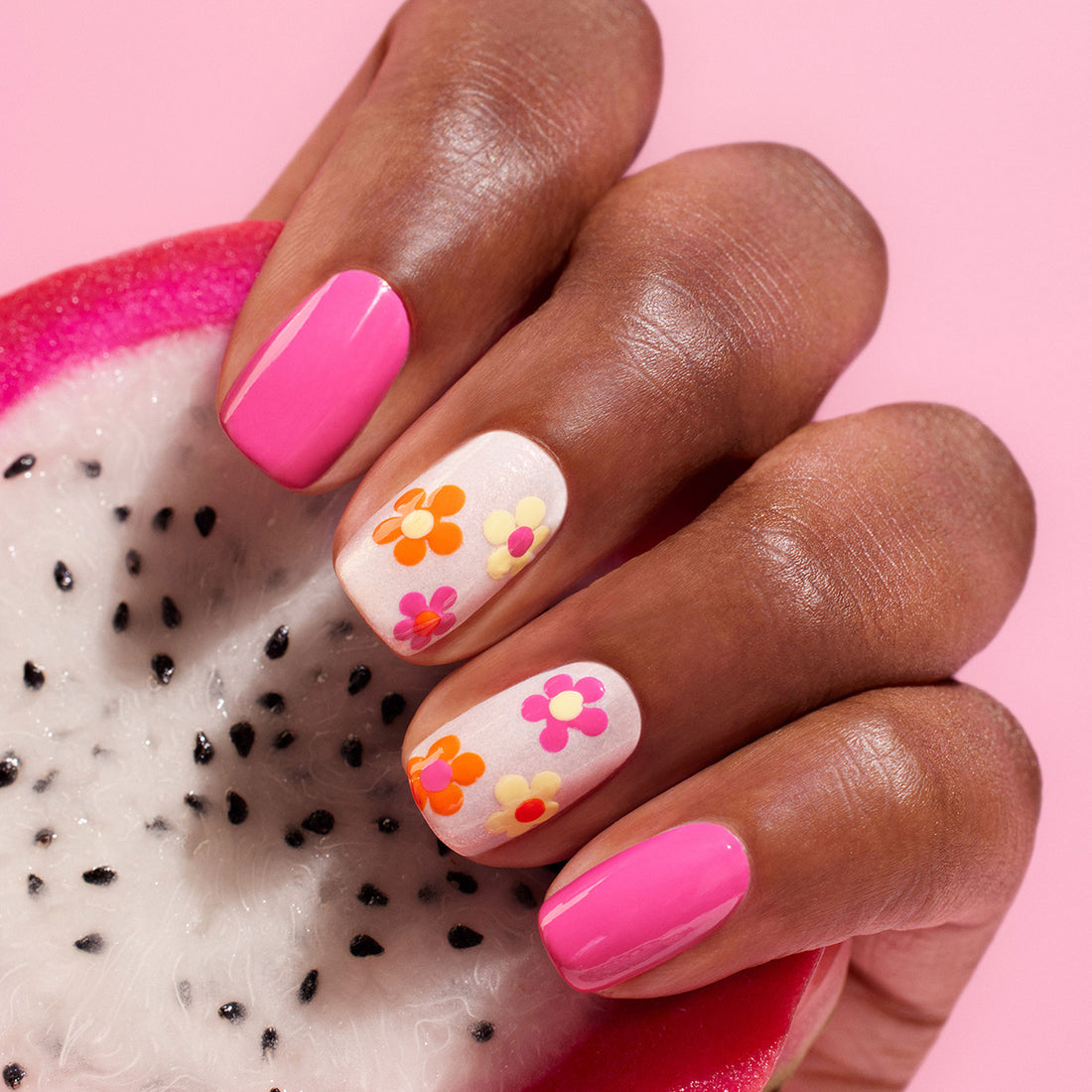 A hand with pink and white floral nail art, created using Manucurist&