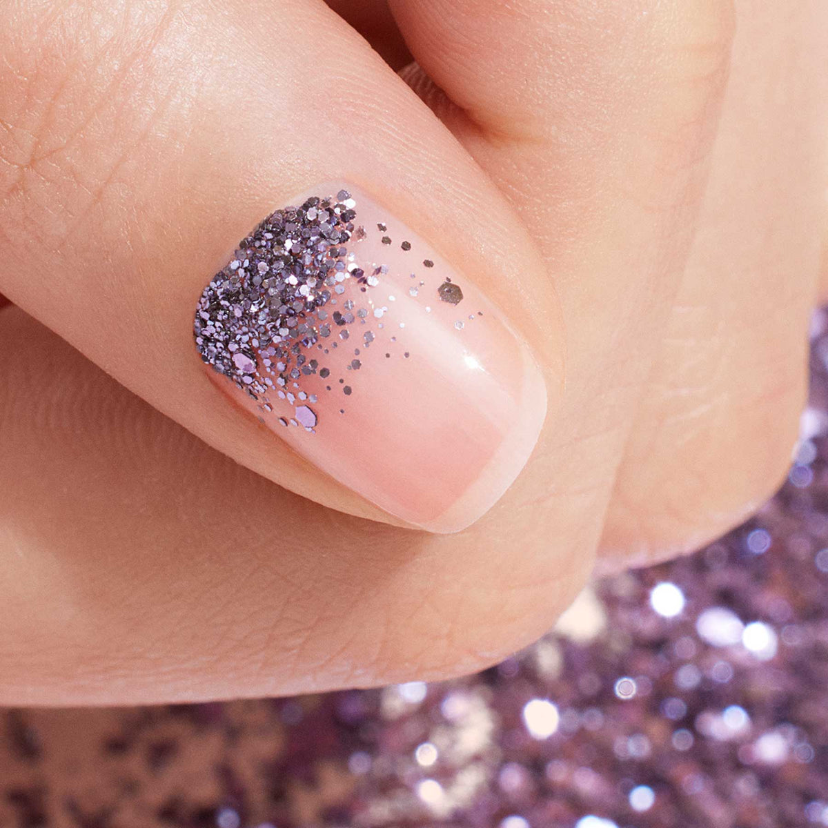 A close-up of a fingernail with clear base polish, decorated at the cuticle with Manucurist&