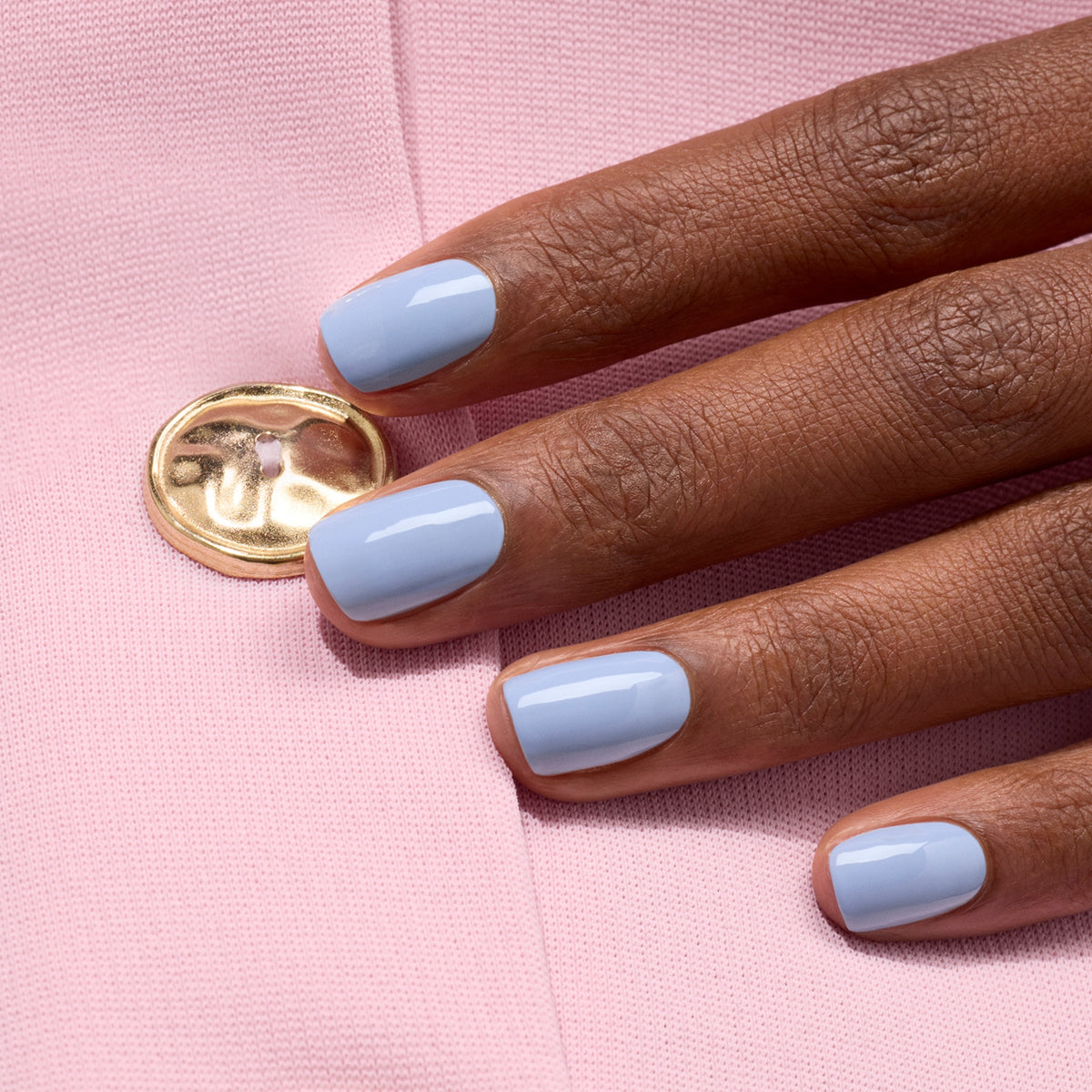 A hand with short, neat nails painted in Manucurist&