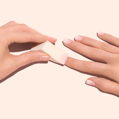 Une main utilise les Éponges Nail Art Manucurist (x4) pour estomper un vernis rose clair, créant un effet Baby Boomer délicat sur les ongles de l&