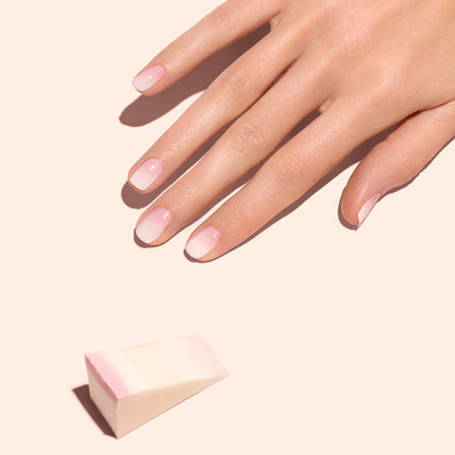 Une main aux ongles naturels soigneusement manucurés repose sur une surface claire. À proximité, les éponges Nail Art Manucurist - x4 suggèrent l’outil parfait pour créer des ongles Baby Boomer doux.