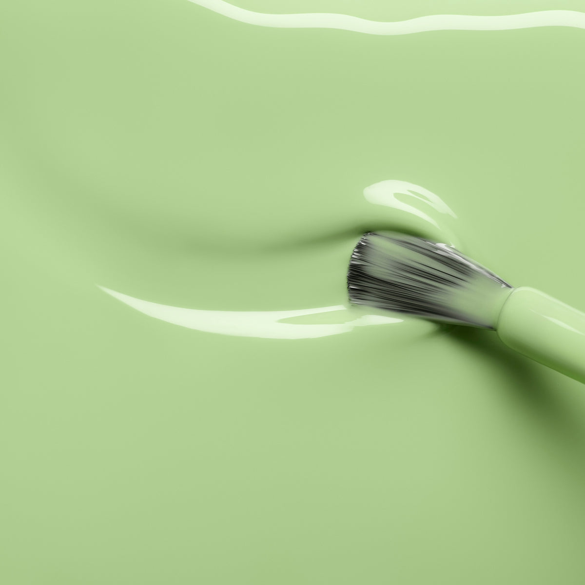 A makeup brush glides through a smooth layer of Manucurist’s Milky Matcha gel polish, creating a soft, wavy texture on the surface with subtle creamy nuances.