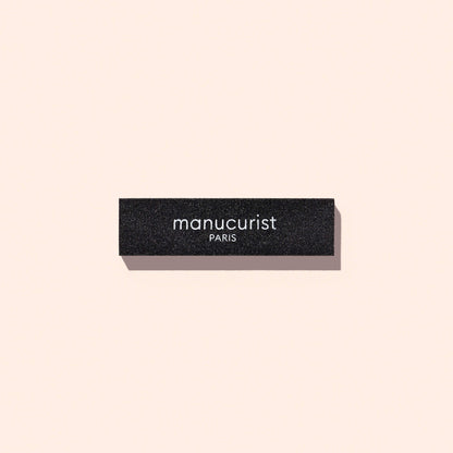 Bloc de dépose rapide Manucurist-us noir et rectangulaire, utilisé pour retirer le Top Coat, avec le nom de la marque imprimé en blanc sur le côté.