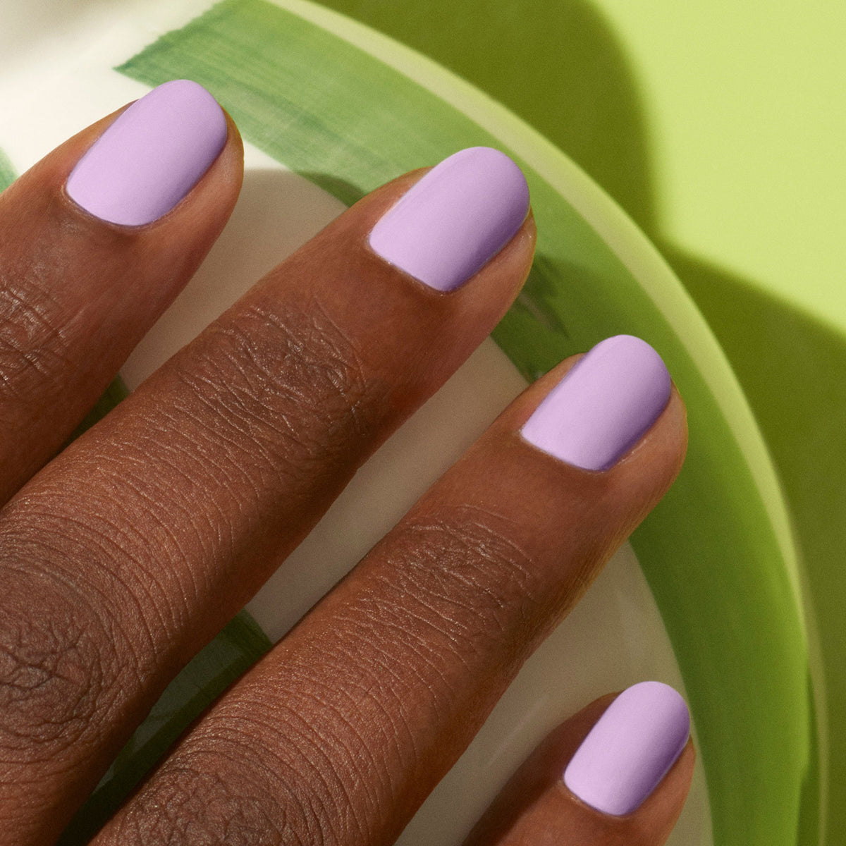 A close-up of a dark-skinned hand with neatly manicured nails painted in Manucurist&