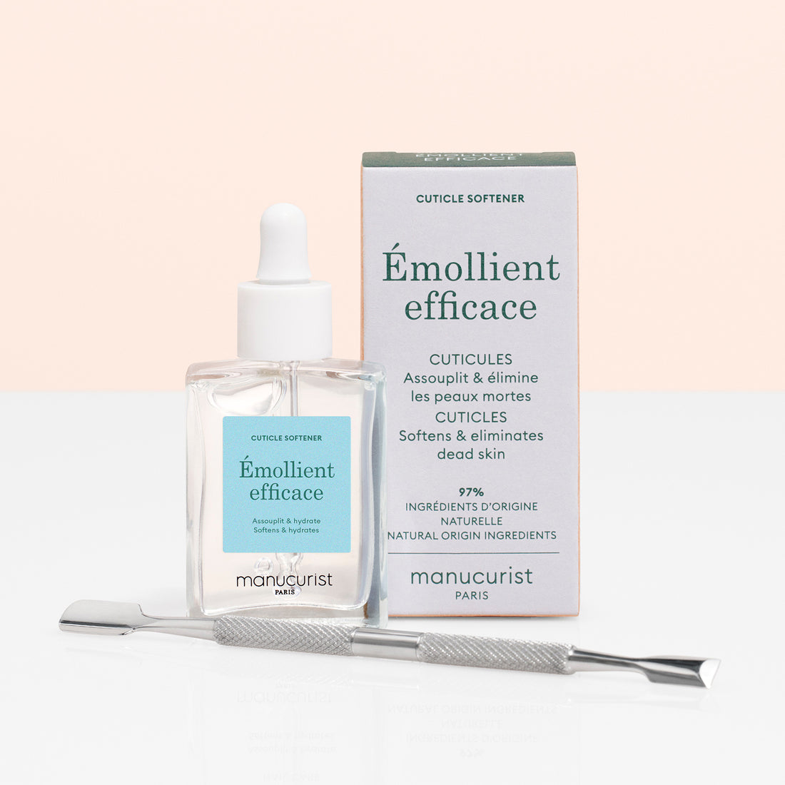 A glass bottle of Manucurist Cuticle Softener  Pusher Duo with a dropper, its box, and a metal pusher on a white surface against a light pink background—ideal for gently softening and removing dead skin around the nail plate.