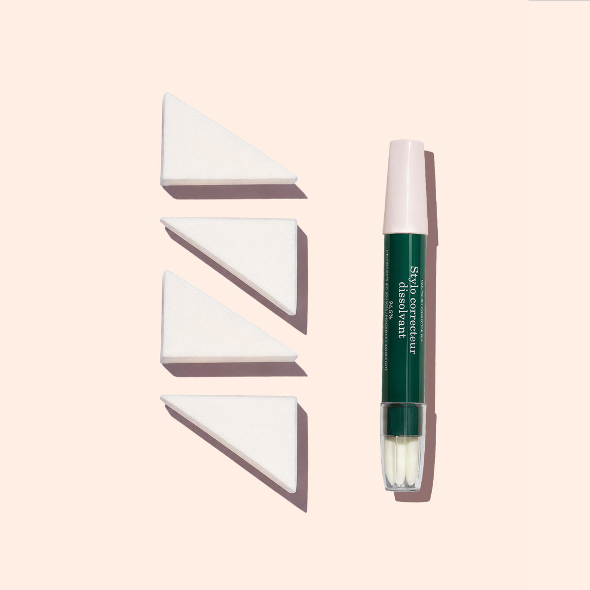 Un pinceau de maquillage à capuchon vert et rose se tient debout à côté de trois éponges Nail Art Manucurist (lot de 4) alignées sur un fond beige clair.
