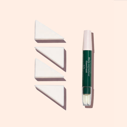 Un pinceau de maquillage à capuchon vert et rose se tient debout à côté de trois éponges Nail Art Manucurist (lot de 4) alignées sur un fond beige clair.