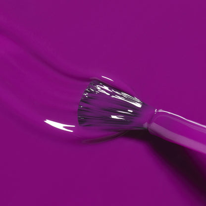 A close-up of Manucurist’s Fizz brush applying glossy violet polish with magenta undertones, smooth strokes visible in the wet finish.