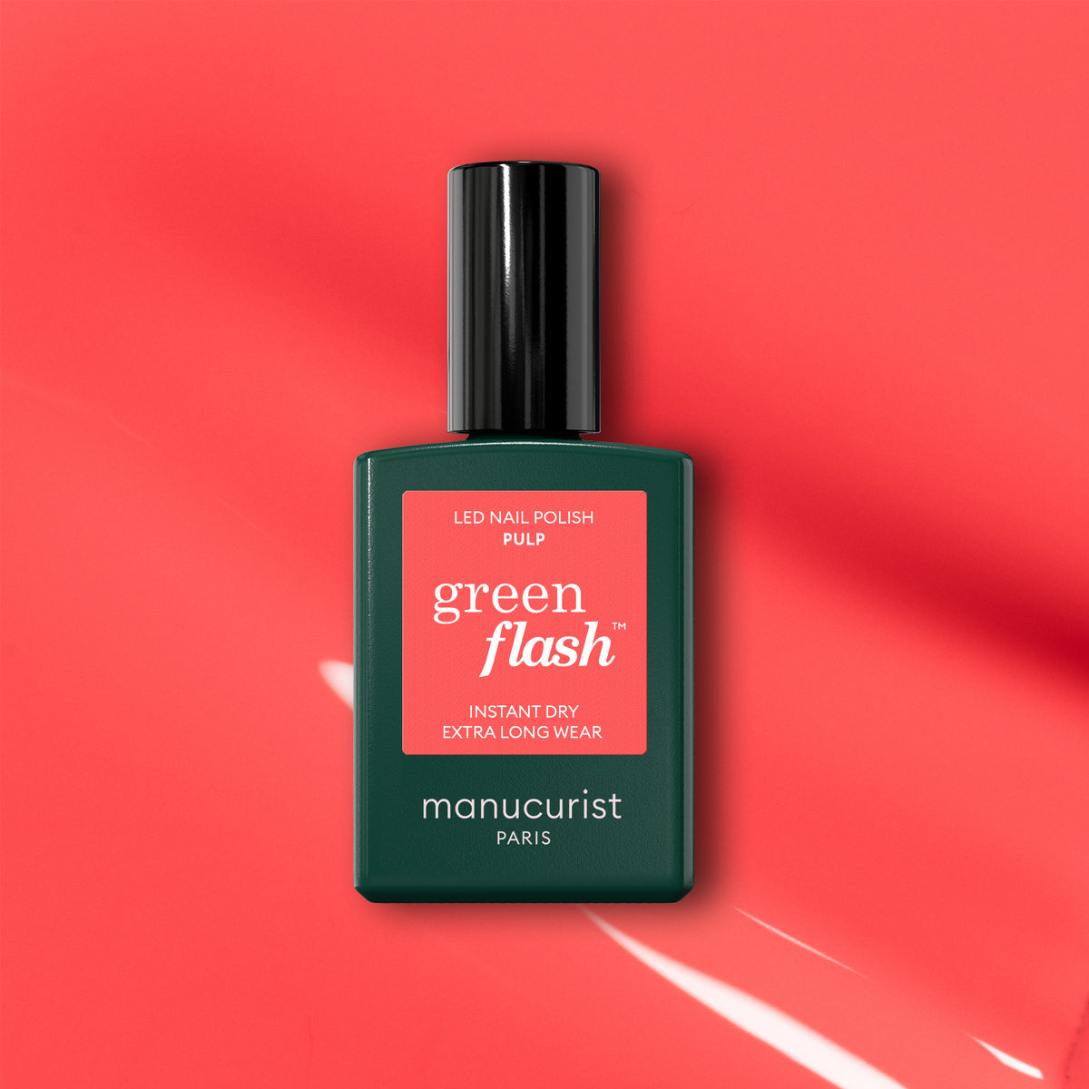 A bottle of Manucurist Pulp gel polish is displayed on a coral pink background with light reflections. The label reads "Pulp, Instant Dry, Extra Long Wear.