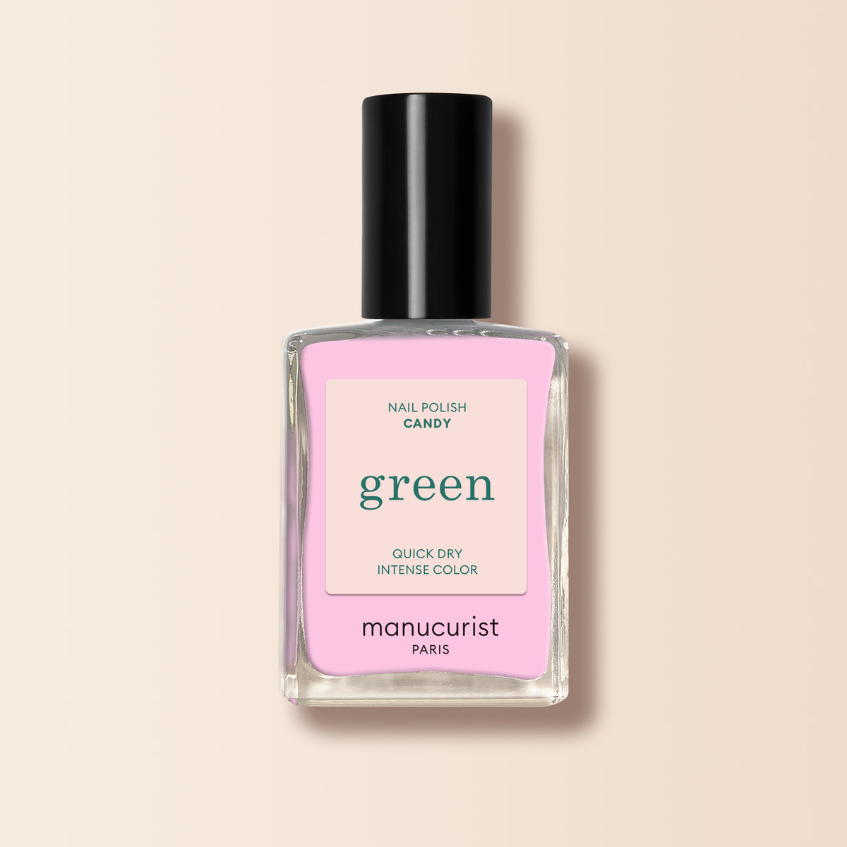 A bottle of Manucurist Candy nail polish with a black cap and a pink label sits against a soft light beige background.