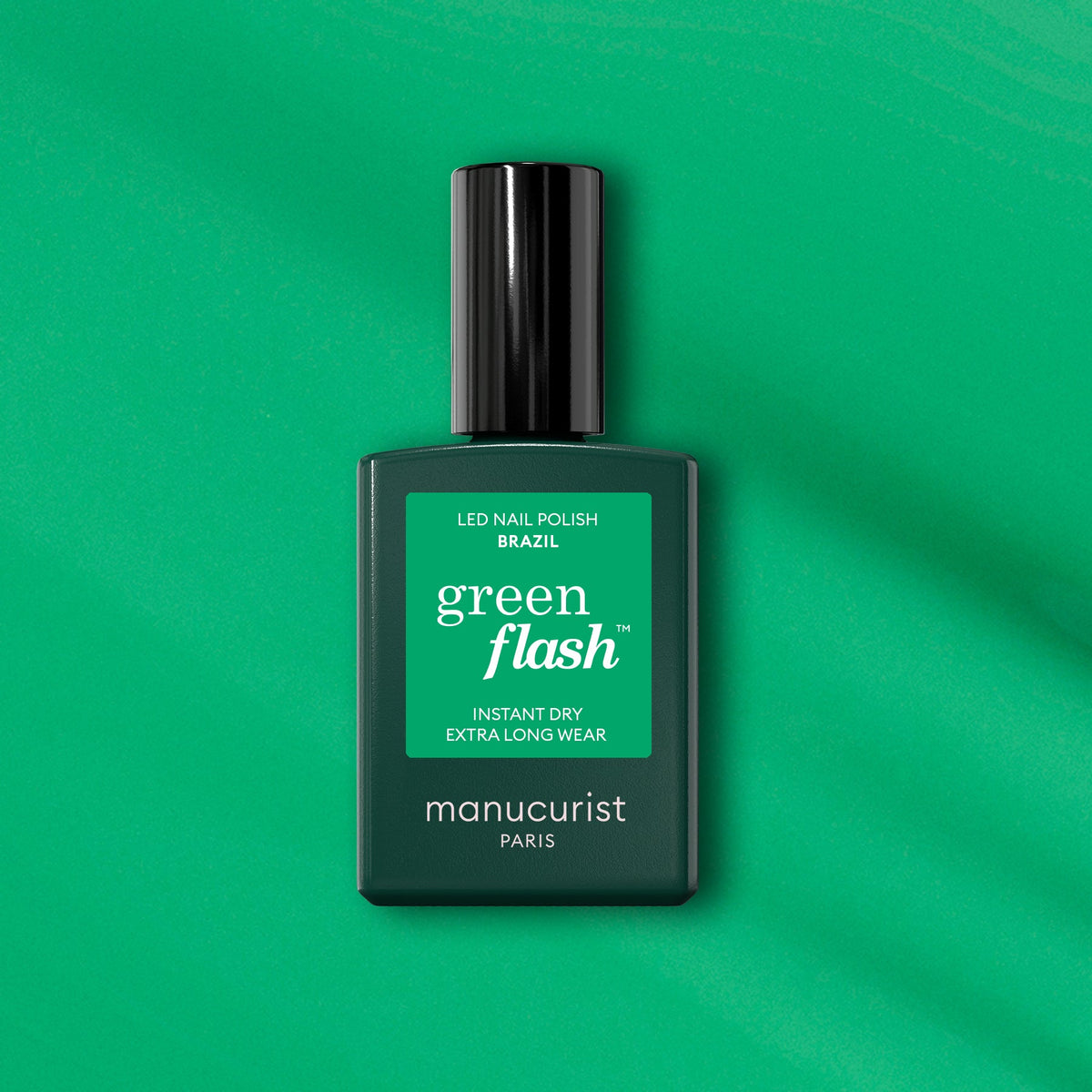 Un flacon de vernis LED Manucurist Brazil Green Flash est posé sur un fond vert, avec un séchage instantané et une tenue extra-longue pour des ongles vert électrique éclatants inspirés de la plage de Copacabana.