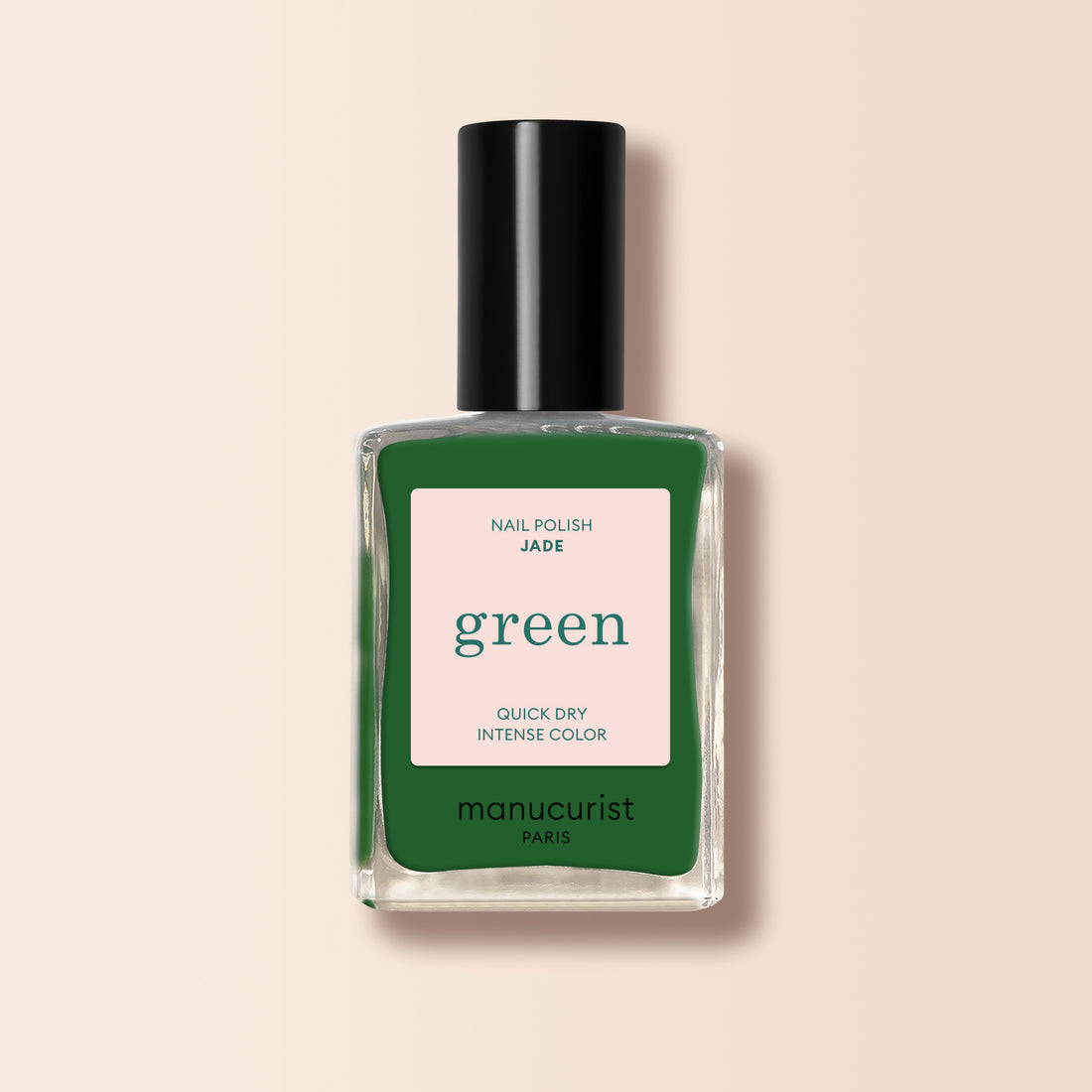 A bottle of Manucurist Jade nail polish in mineral green with cool undertones, dark green shade, black cap, and beige label is shown against a light beige background.