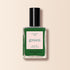 Un flacon de vernis à ongles Manucurist Jade vert minéral aux sous-tons froids, dans une teinte vert foncé, avec un bouchon noir et une étiquette beige, est présenté sur un fond beige clair.