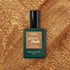 A bottle of Manucurist Shimmer gel polish sits on a sparkling gold surface that matches the cool undertone of the nail polish shade.