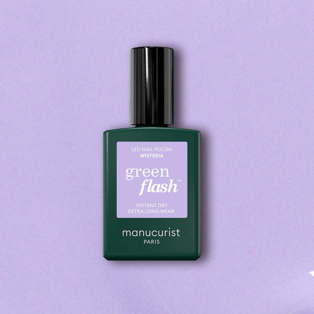 A bottle of Manucurist Wisteria sits against a light lavender background. The dark green bottle has a lavender label and black cap, highlighting this pastel purple gel polish from the brand’s LED-friendly Green Flash range.