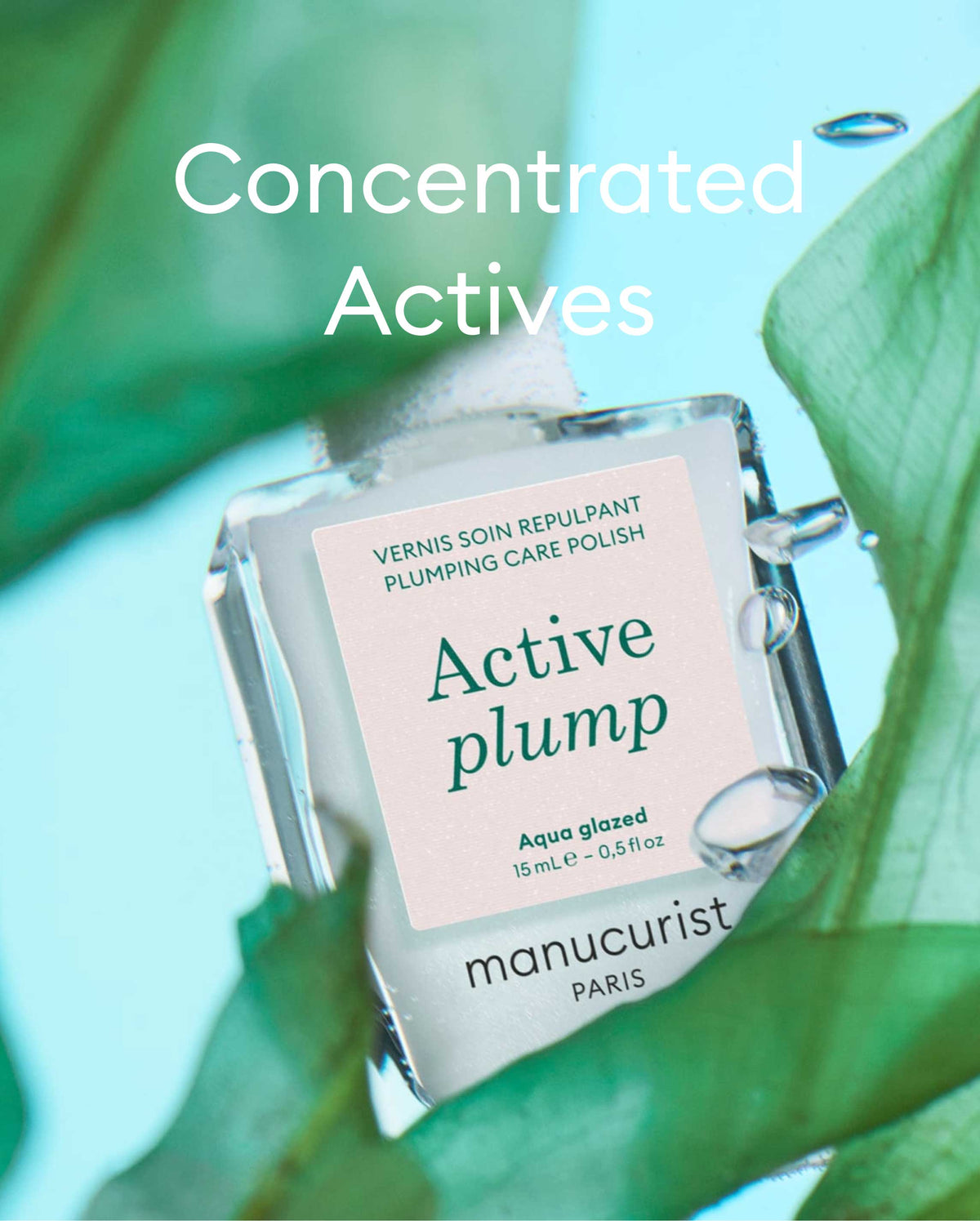 A bottle of Manucurist Paris Active Plump nail polish submerged in water, surrounded by green leaves, with the text Concentrated Actives above.