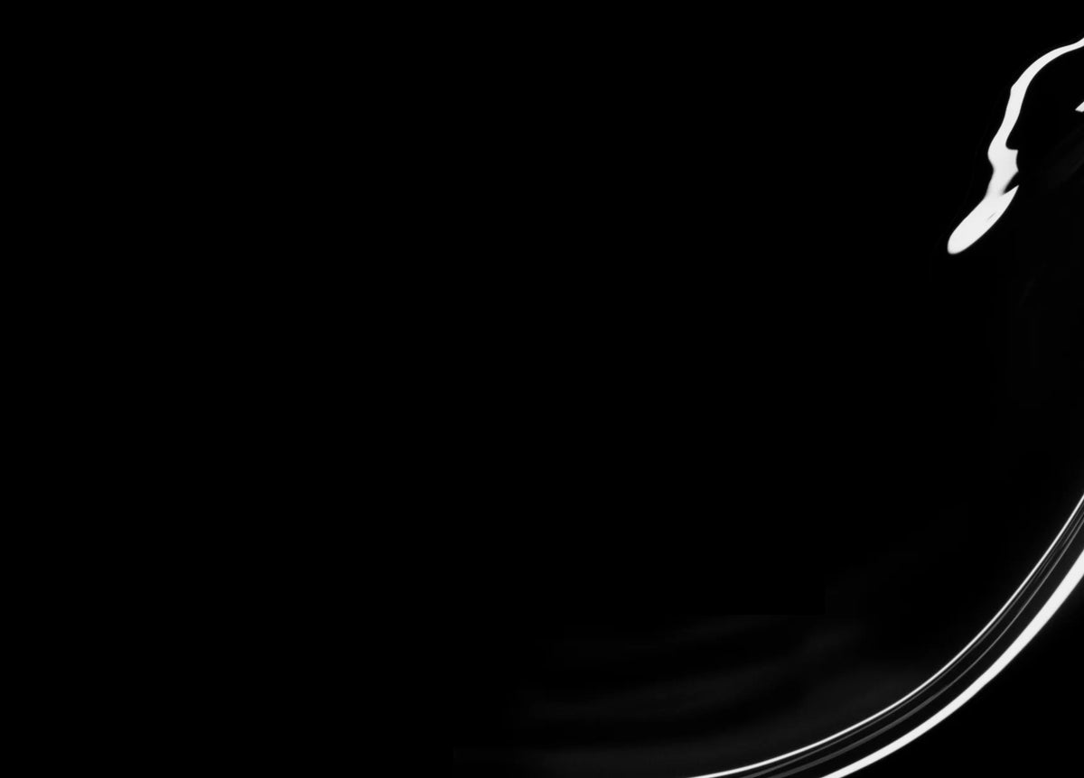 A close-up of a curved glass edge against a black background, with highlights and reflections creating abstract white shapes and lines.