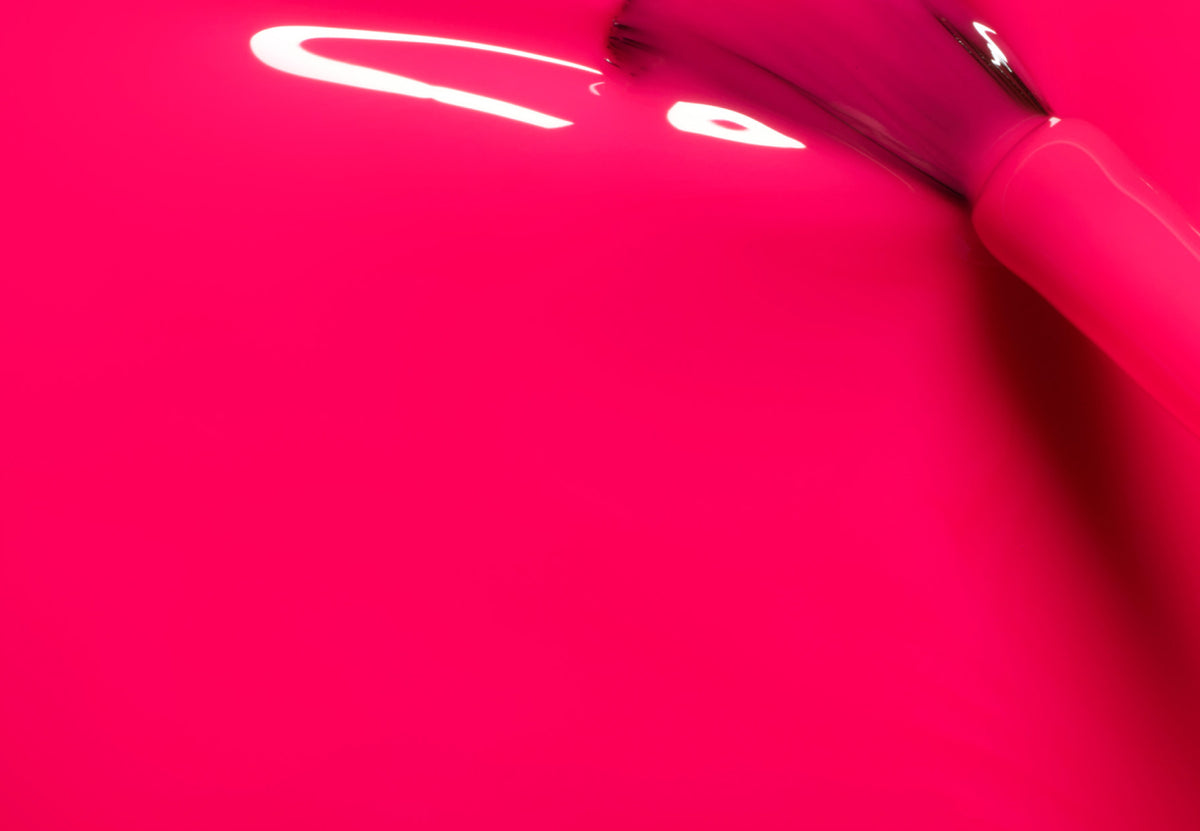 Gros plan d’un pinceau appliquant un vernis à ongles rose vif, avec un vernis lisse et brillant couvrant la majeure partie de la surface.
