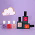 Le coffret Green Flash™ You  Me at a Tea Party de Manucurist présenté sur un fond lavande avec un biscuit souriant en forme de nuage à côté. Certains flacons arborent des illustrations d&