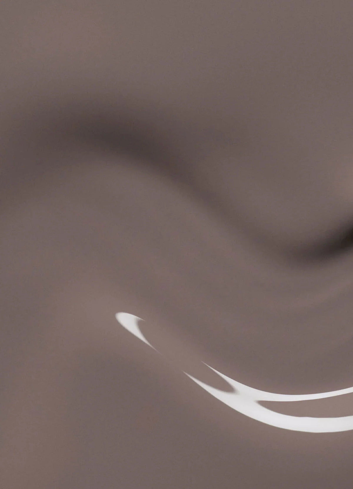 Une surface lisse et abstraite dans des nuances de brun clair, avec de douces vagues et un reflet incurvé de lumière blanche dans le coin inférieur droit.