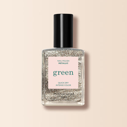 Un flacon de vernis à ongles Metallic Manucurist aux reflets métalliques et à la couleur intense est posé sur un fond rose pâle.