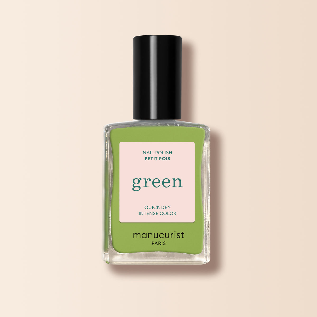 A bottle of Manucurist Green™ nail polish with a black cap, light green liquid, and a label reading Green, Quick Dry Intense Color, Nail Polish Sweet Pea. The background is light beige.